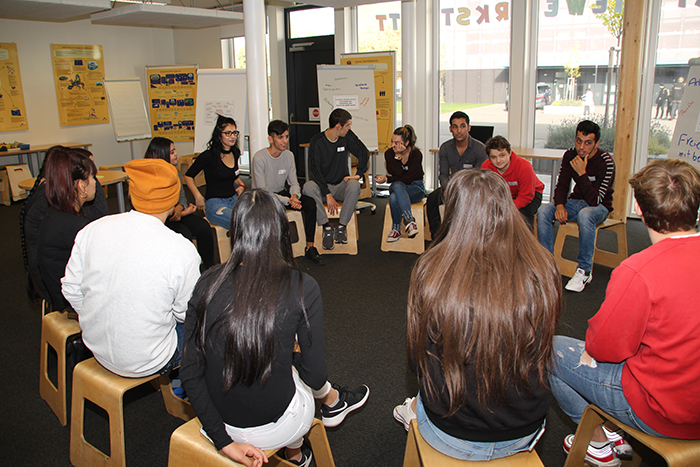 Lehrlinge sitzen im Sesselkreis und diskutieren