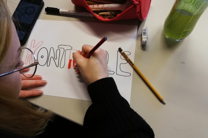 Ein Lehrling sitzt vor einem Tisch mit einem Stift in der Hand und zeichnet.