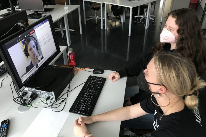 Zwei Lehrlinge sitzen an einem Tisch und schauen auf einen Computerbildschirm