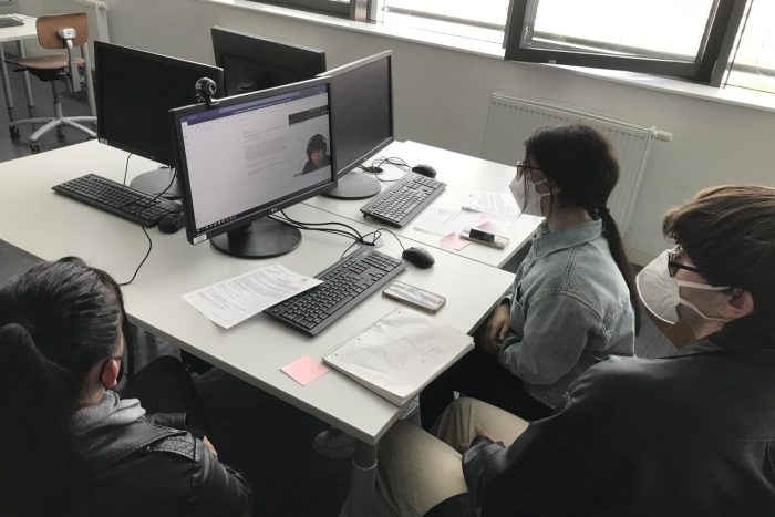Drei Lehrlinge sitzen an einem Tisch mit Computer