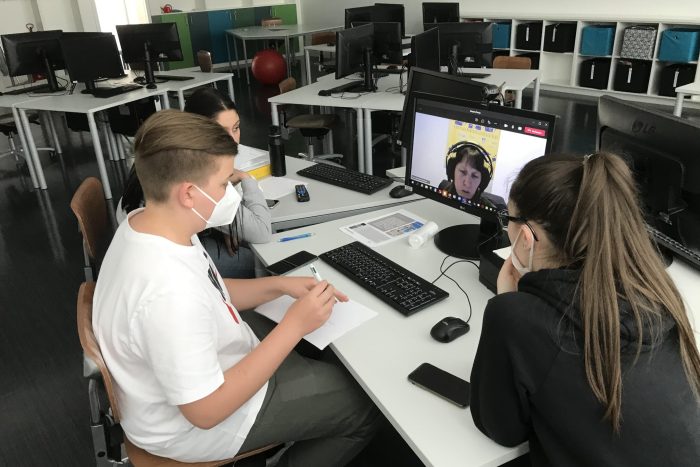 Drei Lehrlinge sitzen an einem Tisch und arbeiten am Computer