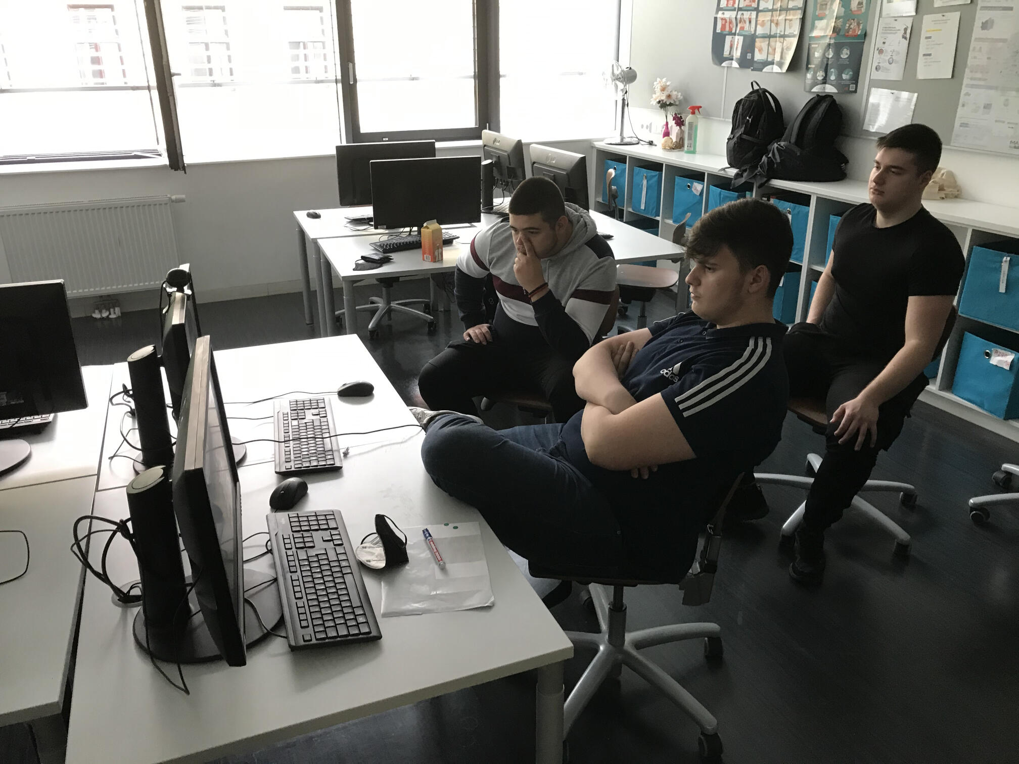 Drei Lehrlinge sitzen an einem Tisch mit Computer
