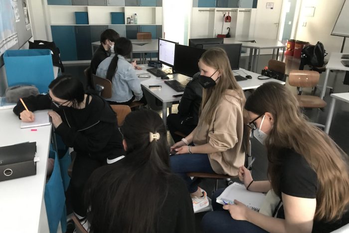 Lehrlinge sitzen im Klassenzimmer an Tischen mit Computer und arbeiten