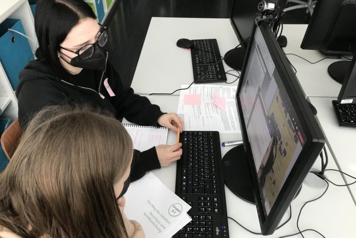 Zwei Lehrlinge sitzen an einem Tisch mit Computer