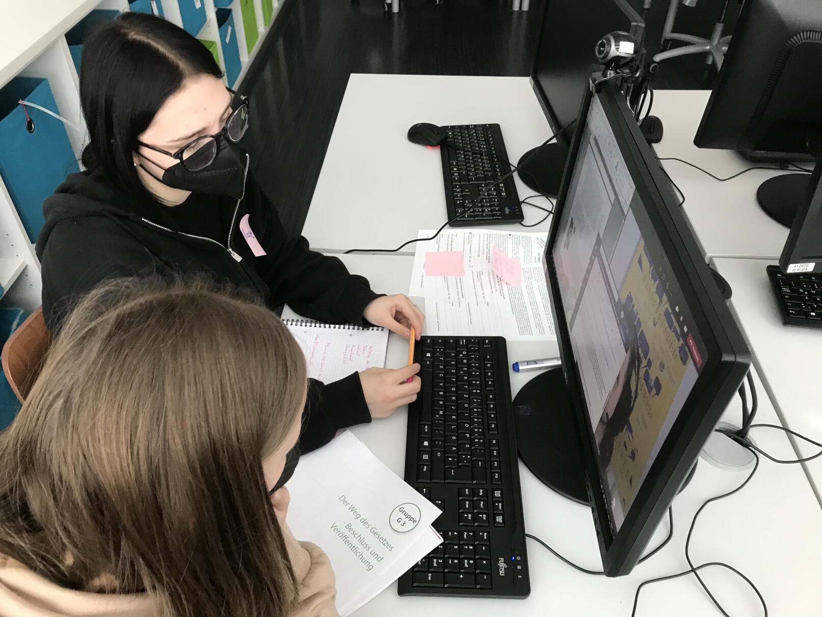 Zwei Lehrlinge sitzen an einem Tisch mit Computer