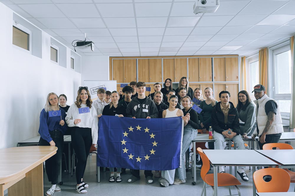 Schüler:innen in einer Klasse halten eine EU-Flagge