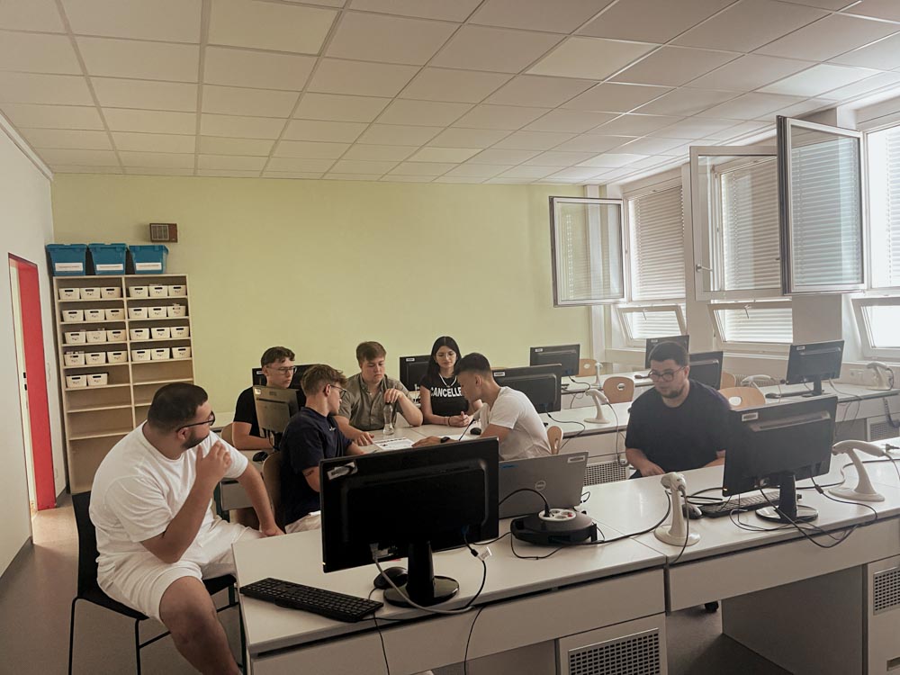 Schüler:innen sitzen im Computersaal und diskutieren