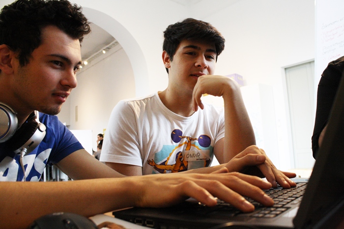Zwei Lehrlinge schreiben einen Artikel am Laptop
