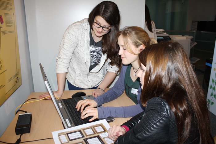 Drei junge Frauen der Lehrlingsgruppe schreiben am Laptop einen Zeitungsartikel